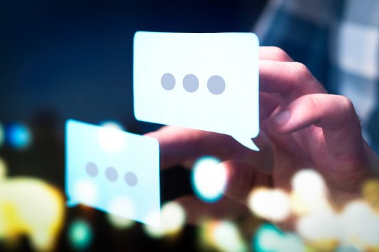 Communication, dialog, conversation on an online forum and internet chatting concept. Business man or social media consultant holding speech bubbles in futuristic modern abstract space.