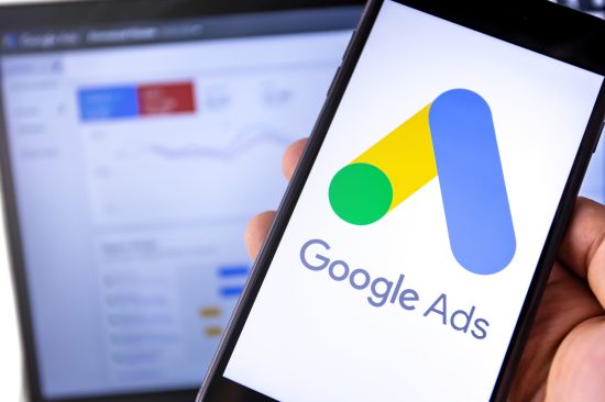 smartphone with Google Ads on the screen and display notebook background. Ads is a service of contextual, basically, search advertising from Google. Moscow, Russia - August 25, 2019