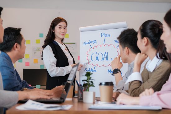 Portrait businesswoman standing by whiteboard and giving presentation to colleagues during meeting in conference room  . explaining something to his colleagues. Project results.