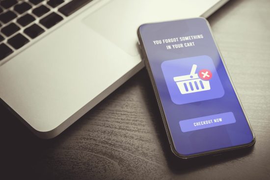 Abandoned Shopping Cart Recovery using Email Marketing Strategies. Smartphone with open email reminder message, effectiveness of targeted email in boosting sales, recovering abandoned shopping carts.